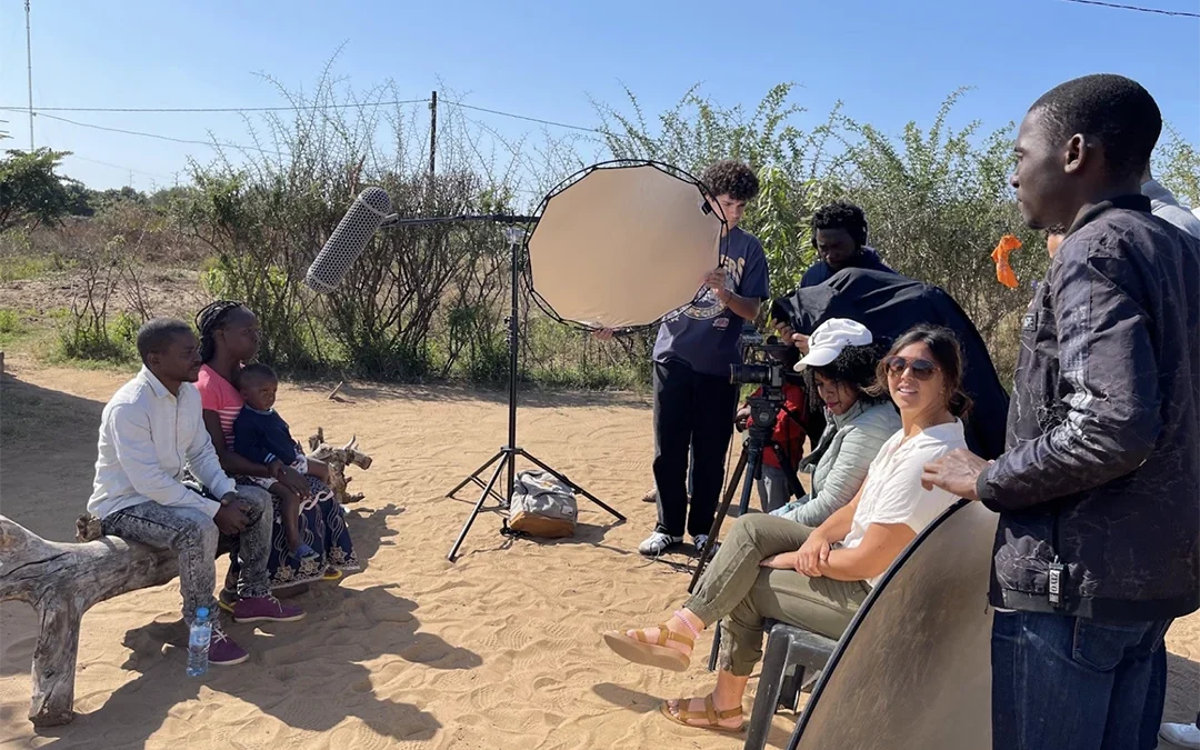A group of filmmakers and a family in Mozambique filming interviews.
