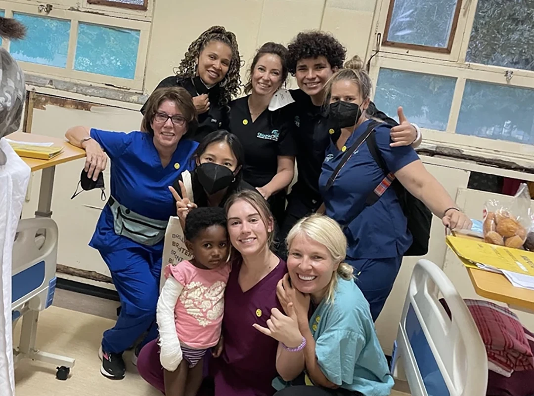 A group of physicians with a patient smiling in a hospital room.