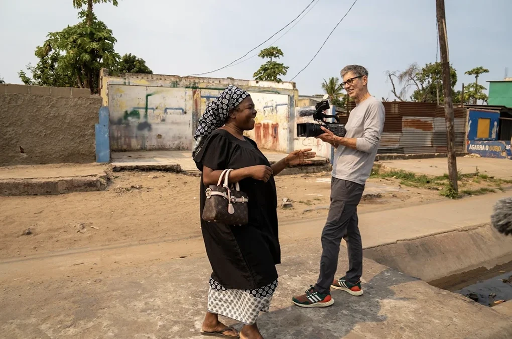 A woman joyfully walking down the street in Mozambique and being filmed for the Ohana One documentary.